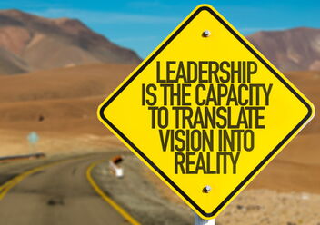 Gelbes Schild am Straßenrand in der Wüste. Auf dem Schild steht "Leadership is the capacity to translate vision into reality"