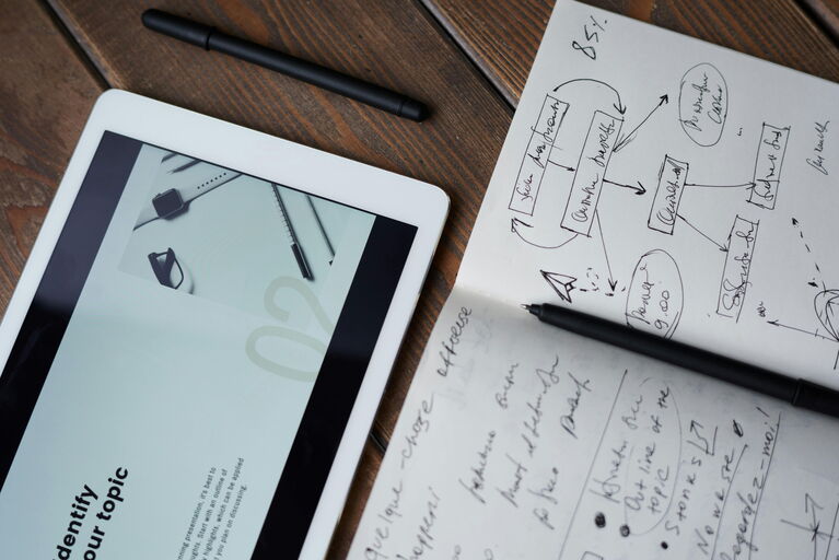 Tablet, davor ein beschriebenes Blatt und ein Stift